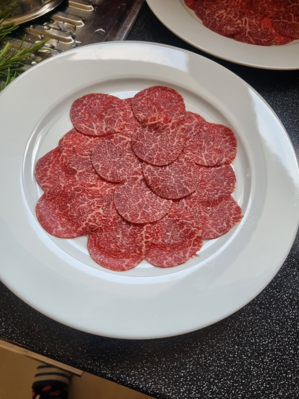Wagyu Carpaccio, rund angerichtet auf weissem Teller